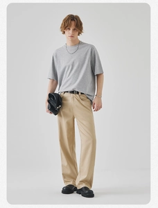 Detail of grey crewneck t-shirt styled with khaki trousers and black accessories