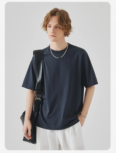 Detail view of navy blue cotton T-shirt styled with a black leather crossbody bag