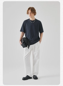 Detail view of navy blue short sleeve T-shirt paired with white wide-leg pleated trousers