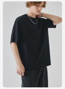 Detail view of a men's black crewneck cotton T-shirt styled with a silver chain necklace