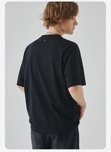 Back view of a black relaxed fit cotton T-shirt featuring a minimalist white dot detail