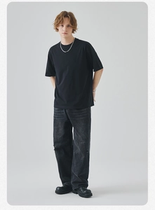 Detail of oversized black crew neck t-shirt paired with distressed grey ripped denim jeans