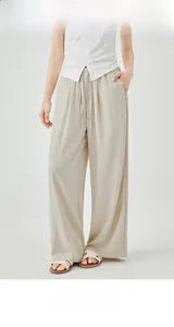 Detail of cream high-waisted wide leg trousers with adjustable drawstring and fabric texture