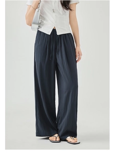 Detailed view of dark blue wide-leg trousers with drawstring waist and pleated texture