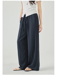 Detailed view of dark loose wide-leg trousers with drawstring elastic waistband