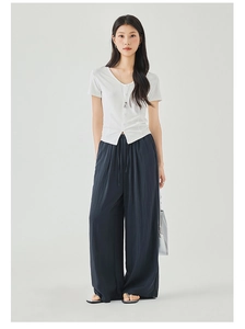 Detail of loose-fit navy wide-leg trousers with drawstring waist and white V-neck top