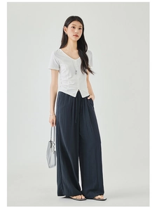 Detail of white V-neck knit top and navy wide-leg trousers with drawstring waist