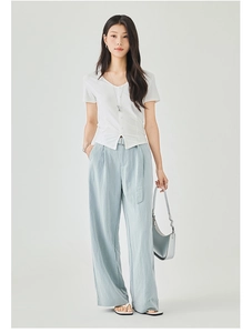 Dettaglio dei pantaloni a gamba larga azzurri con cintura abbinata e top bianco con scollo a V
