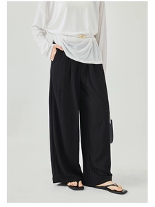 Detail of high-waist wide-leg black trousers featuring loose drape and tie waist design