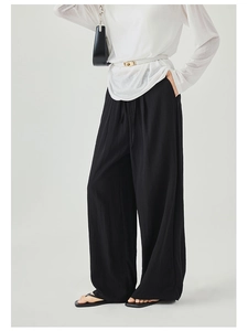 Macro detail of black wide-leg trousers featuring a high waist with a stylish self-tie belt