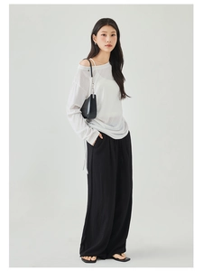 Detail of loose black pleated wide-leg pants with elastic drawstring waist and flowy texture