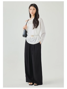 Detail showing high-waisted black wide-leg trousers with elegant drape and lace-up waist detail