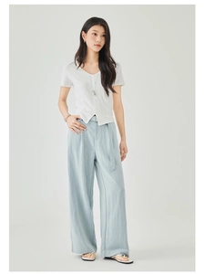 Dettaglio del top bianco a maniche corte con scollo a V e pantaloni larghi in lino azzurro