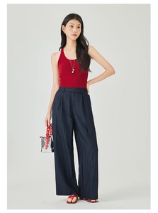 Dettaglio dei pantaloni a gamba larga a vita alta con top smanicato rosso e accessori