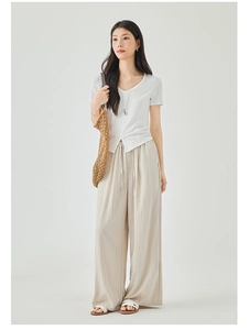 Detail of white V-neck short sleeve knit top with buttons and beige wide-leg trousers