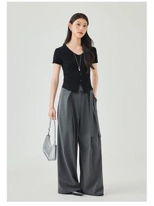 Detail of a black V-neck short sleeve knit top paired with grey wide leg trousers