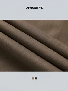Dettaglio dei pantaloni dritti marrone scuro che mostra la trama liscia del tessuto twill