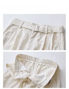 Dettaglio dei pantaloni larghi crema con vita elastica e cintura in tessuto con fibbia coordinata