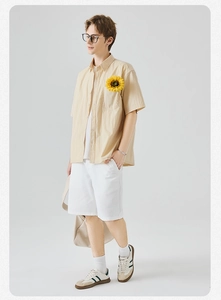 Dettaglio di camicia beige a maniche corte da uomo con taschino e pantaloncini bianchi