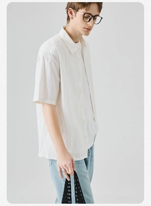 Dettaglio di una camicia bianca a maniche corte da uomo con bottoni e texture naturale