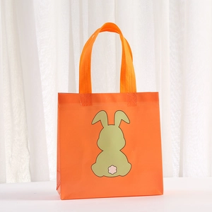Macro view of orange non-woven rabbit gift bag with cartoon bunny print and sturdy handles
