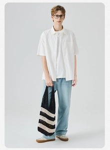 Camicia bianca a maniche corte da uomo con jeans blu chiaro e borsa in maglia