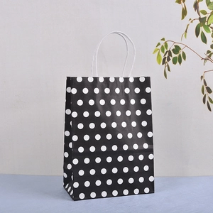Detail view of black kraft paper gift bag with white polka dots and twisted handles