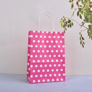 Detail of rose pink kraft paper gift bag with white polka dots and sturdy twisted rope handles