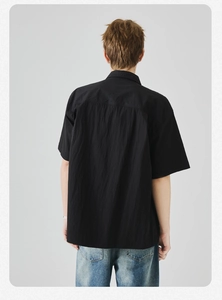 Dettaglio del retro di una camicia nera a maniche corte con cucitura orizzontale