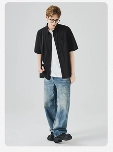 Camicia nera a maniche corte da uomo con t-shirt bianca e jeans in denim a gamba larga