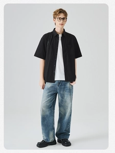 Dettaglio completo della camicia nera a maniche corte, t-shirt bianca e jeans blu larghi
