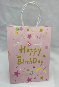 Close-up of pink kraft birthday gift bag with golden crown and colorful party icons
