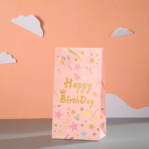 Pink birthday party gift paper bag with golden Happy Birthday lettering and colorful balloons