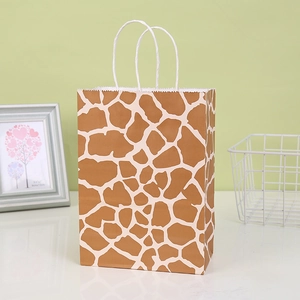 Detail of giraffe print kraft paper gift bag with white twisted rope handles on a table