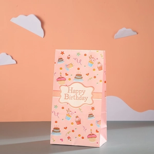 Pink paper birthday party gift bag with cupcake motifs and Happy Birthday text print