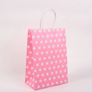 Sac cadeau en papier kraft rose à pois avec des poignées en corde torsadée blanche