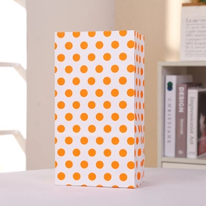 Vista detallada de una bolsa de regalo de papel blanco con lunares naranjas