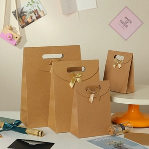 Set of four brown kraft paper gift bags with cutout handles and elegant ribbon bows