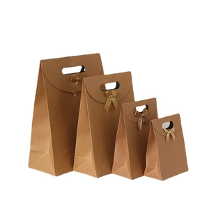 Set of four brown kraft paper gift bags with golden ribbon bows in graduated sizes