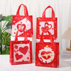 Détail de quatre sacs cadeaux rouges en intissé avec motifs de cœurs pour la Saint-Valentin