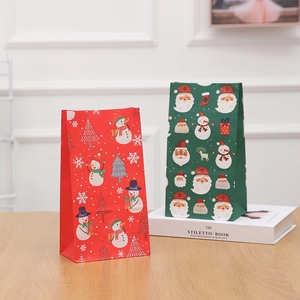 Christmas kraft paper gift bags with festive snowman and Santa prints on wooden surface