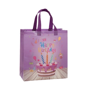 Purple non-woven birthday gift bag with cake print and reinforced handles on white background