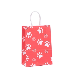 Coral red gift bag with white paw prints and white rope handles for party favors