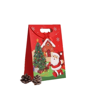 Christmas kraft paper gift bag with red bow handle and festive tree illustration