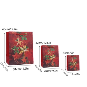 Three sizes of red Christmas gift bags with gold stars and red handles on white background