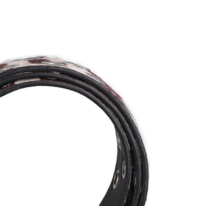 Gedetailleerde weergave van koeienprint faux haar en metalen oogjes op de leren riem