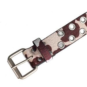 Detail van koeienprint riem met ponyhaar textuur en dubbele metalen oogjes