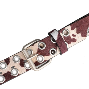 Detailopname van de riem met koeprint en dubbele rij zilveren metalen ogen