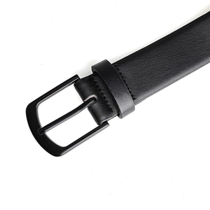 Detailed view of black faux leather belt with matte black metal pin buckle and textured strap