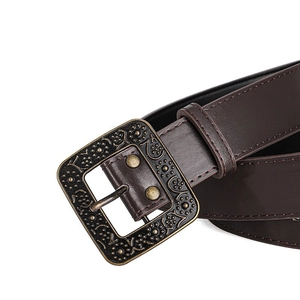 Detail of vintage bronze square buckle with floral relief on dark brown leather belt